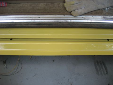 1978 Ford Bronco - Close-up of a yellow interior door sill with metal trim and carpet, a gloved hand is visible.