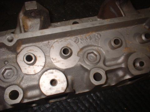 1964 Ford Galaxie - Close-up view of an engine cylinder head, showing various bolt holes and ports.