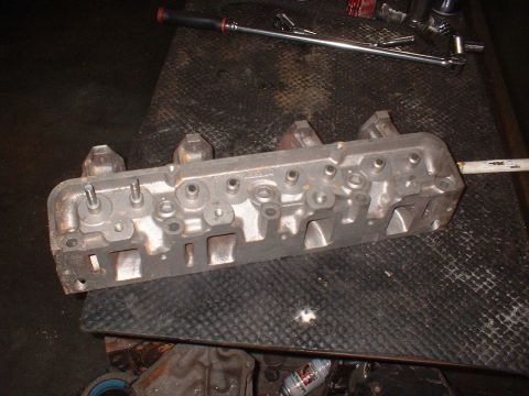 1964 Ford Galaxie - Engine cylinder head on a workbench, with tools in the background.