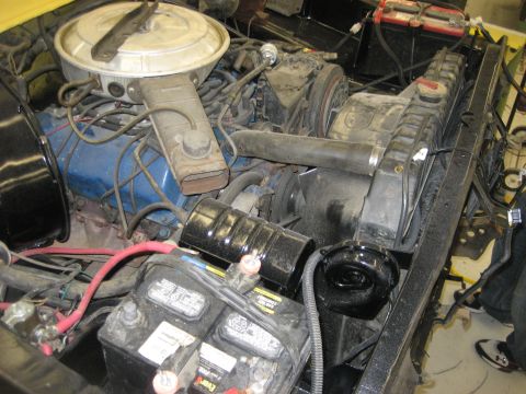 1978 Ford Bronco - The engine bay of a yellow 1978 Ford Bronco is shown, a blue engine block and dual batteries.
