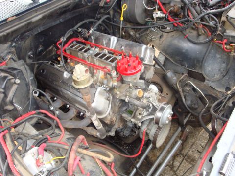 1989 Ford Bronco - Close-up of an engine bay a V8 Racing valve cover and prominent red wiring.