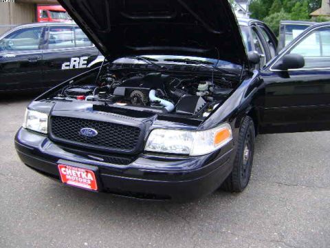 2003 Ford Crown Victoria - A black 2003 Ford Crown Victoria is shown with its hood open, revealing the engine compartment. Another vehicle is parked behind it.