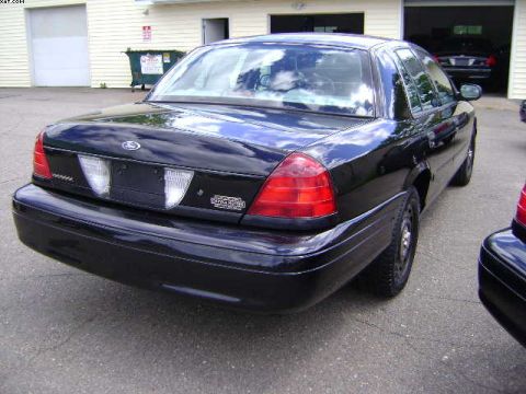 2003 Ford Crown Victoria - Rear view of a black 2003 Ford Crown Victoria, parked next to another vehicle.