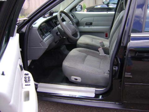 2003 Ford Crown Victoria - The interior of a black sedan is shown, cloth seats and the driver's side dashboard.