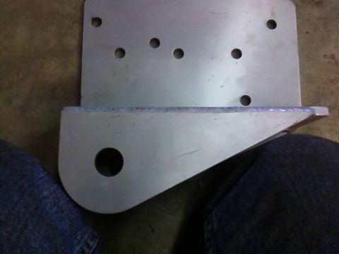 1995 Ford Bronco - A metal bracket with several drilled holes and a large circular opening is shown.