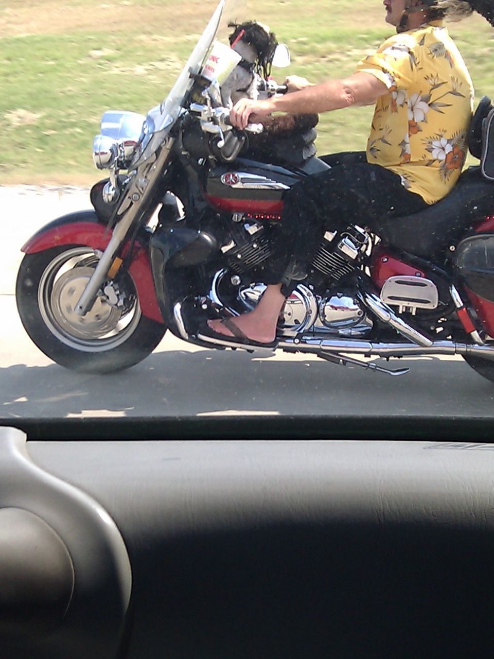 Red and black motorcycle with a rider wearing a yellow floral shirt and flip-flops