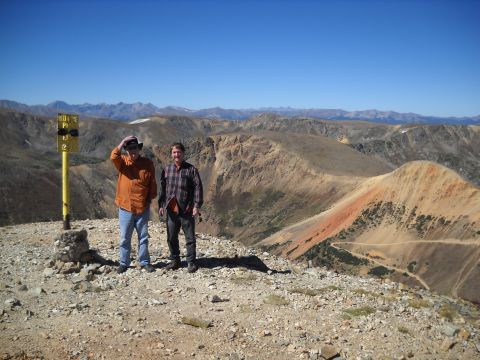 1986 Ford Bronco II - Two men pose for a photo on a mountain summit, with a vast mountainous landscape stretching out behind them.