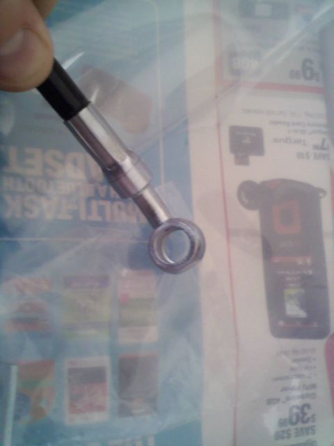 1994 Ford Bronco - A close-up of a metal brake line fitting, likely a replacement part, is held against a background of a retail catalog.