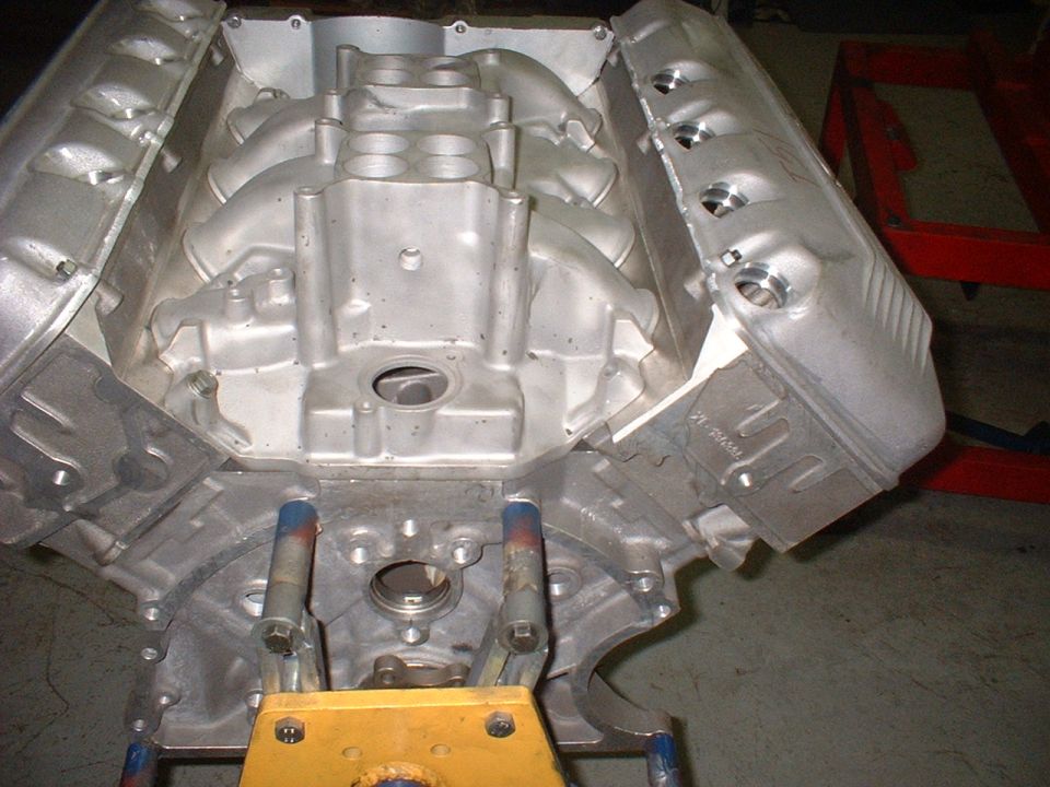 Aluminum engine block with intake manifold and valve covers. Engine is on a stand
