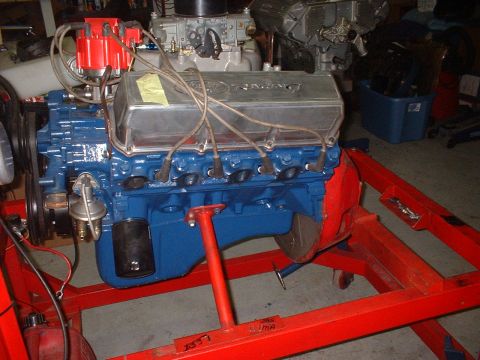 1971 Ford Ranchero - A blue V8 engine with chrome valve covers is mounted on a red engine stand in a garage setting.
