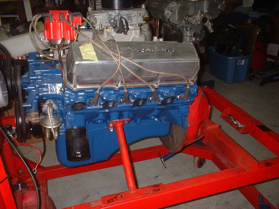 Blue V8 engine with chrome valve covers on a red stand