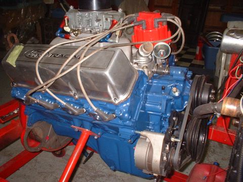 1971 Ford Ranchero - A Ford V8 engine mounted on a red engine stand in a garage, painted Ford-blue with polished 'Ford Racing' valve covers, a Holley four-barre…