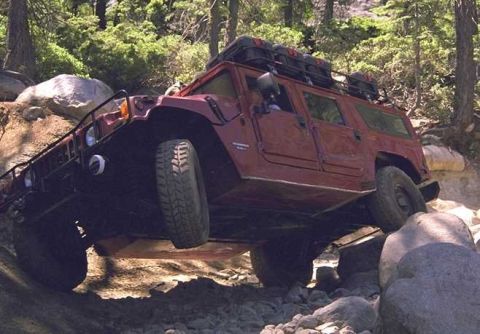 1998 Ford Crown Victoria - A red Hummer H1 navigates a challenging rocky trail, demonstrating its off-road capabilities.