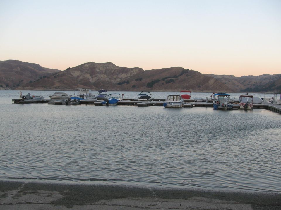 Boats moored on a dock with hills in the background