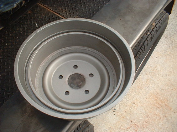 Cleaned gray brake drum with 5-lug pattern resting on a tire