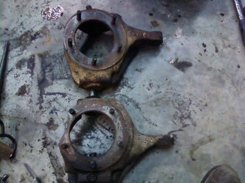 1995 Ford Bronco - Two rusty metal components with visible part numbers sit on a dirty concrete surface.