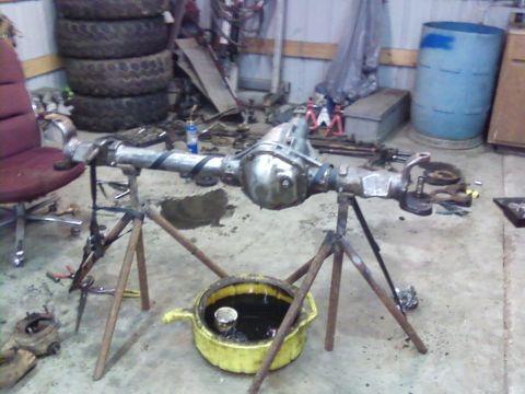 1995 Ford Bronco - An axle assembly is being worked on in a garage setting, with tools and tires visible in the background.