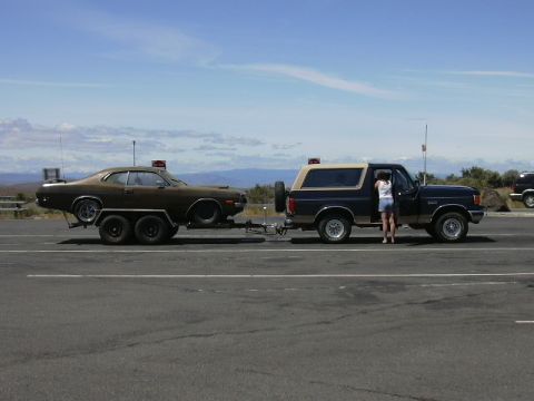 1991 Ford Bronco - A Ford Bronco is seen towing a classic car on a trailer on a sunny day.