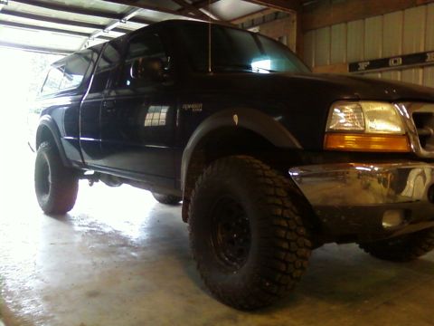 2000 Ford Ranger - This black Ford Ranger pickup truck is equipped with a camper shell and off-road tires.