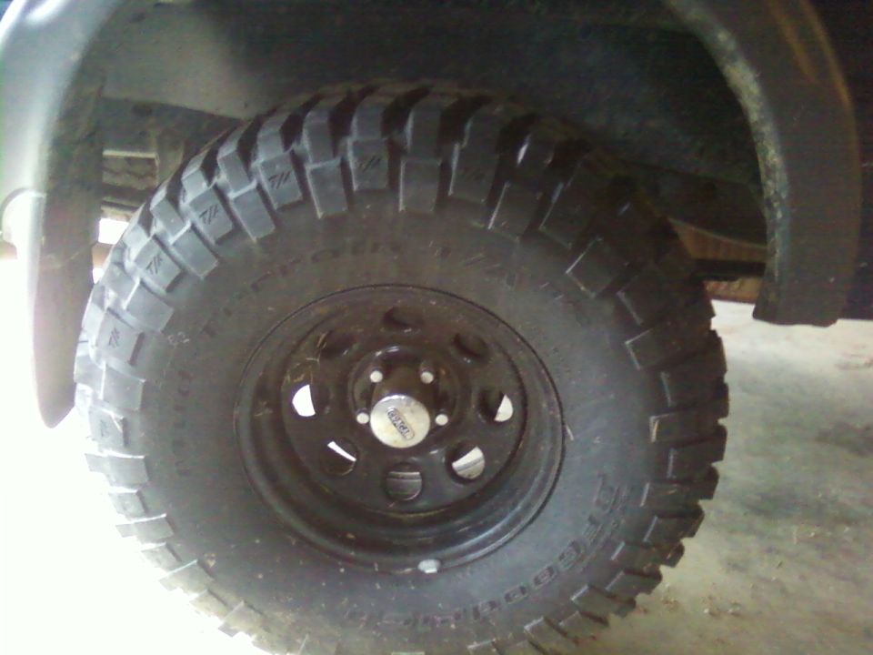 Black steel wheel with BFGoodrich Mud-Terrain T/A tire under fender on concrete floor