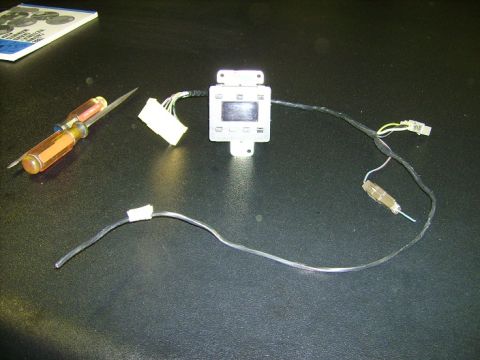 1988 Ford Crown Victoria LTD - A car dashboard control module with attached wiring and a screwdriver are laid out on a dark surface.