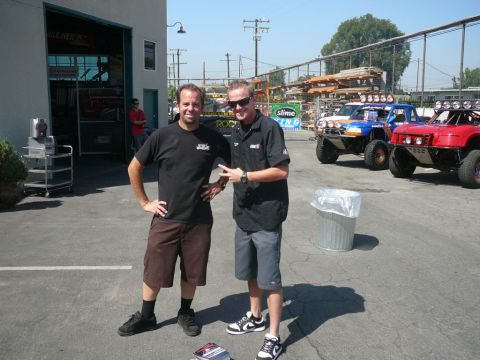 1988 Ford Bronco - Two men stand in front of three off-road vehicles parked in a lot.