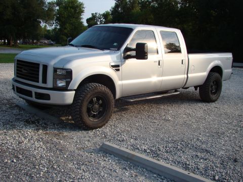 2008 Ford F-250 - A silver 2008 Ford F-250 pickup truck is parked on a gravel lot under a bright sky.