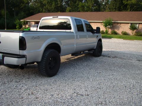 2008 Ford F-250 - A silver 2008 Ford F-250 pickup truck is parked on a gravel surface in front of a brick building.
