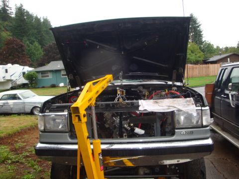 1989 Ford Bronco - A 1989 Ford Bronco's engine bay is exposed for repair, with a yellow engine hoist in place.