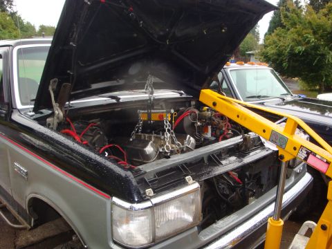 1989 Ford Bronco - Engine removal in progress with a hoist; a second truck is parked nearby.