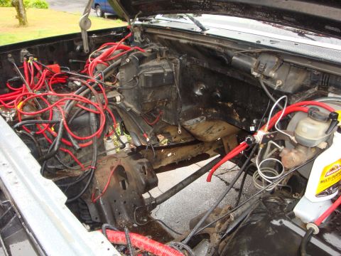 1989 Ford Bronco - The engine bay is exposed, showing a complex network of red wiring and a brake fluid reservoir.
