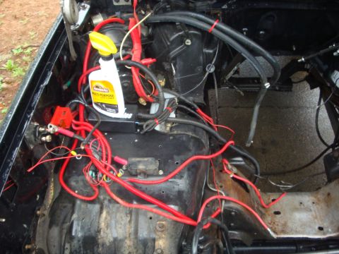 1989 Ford Bronco - The engine bay is filled with red wiring and a bottle of cleaning spray is visible.