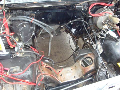1989 Ford Bronco - The engine bay is mostly empty, with the engine removed and various wires and components visible.