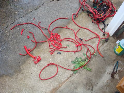 1989 Ford Bronco - A disassembled red wiring harness lies on a wet concrete surface, with tools nearby.