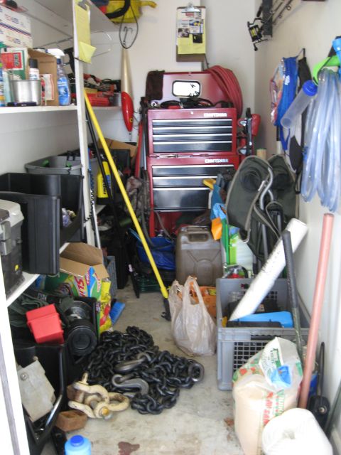 1986 Ford Bronco - A disorganized garage space is filled with tools, storage bins, and miscellaneous items, including a prominent red toolbox.