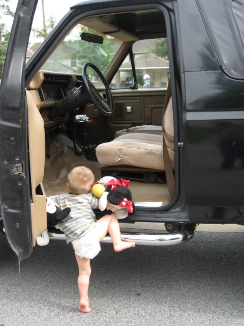 1986 Ford Bronco - A young child enters the interior of an SUV, which appears to be from the 1980s.