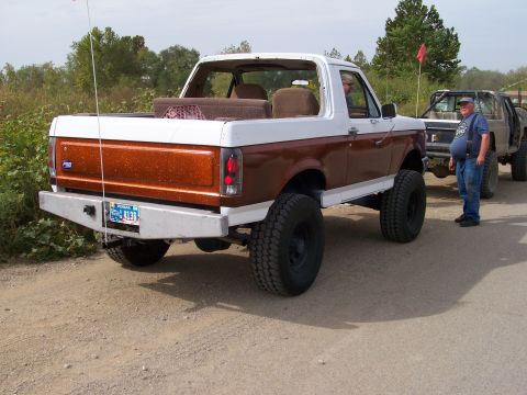 1989 Ford Bronco - This lifted 1989 Ford Bronco features a two-tone brown and white paint scheme and an aftermarket rear bumper.