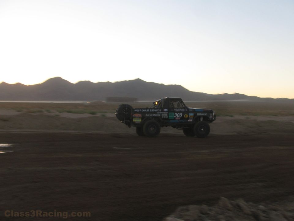 Number 300 off-road race truck on desert track at dusk
