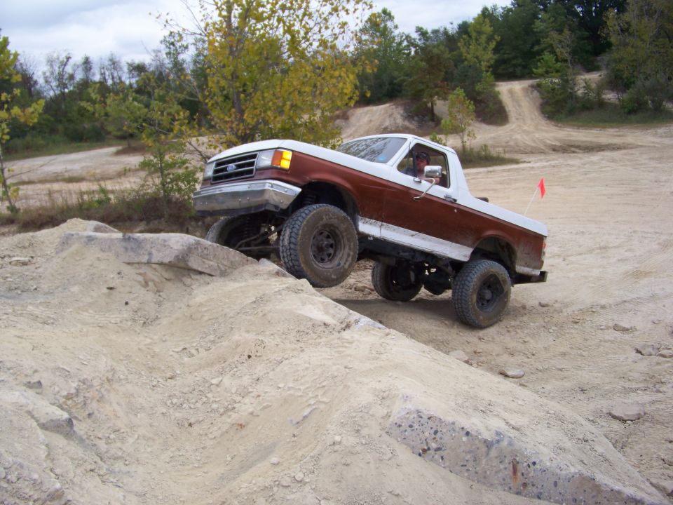 Brown and white Ford Bronco climbing a rocky incline