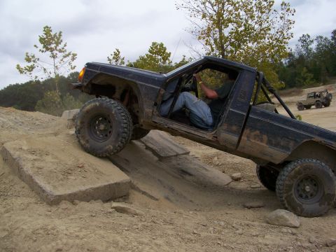 1989 Ford Bronco - Off-road Jeep Comanche navigates a challenging dirt course, with another vehicle in the distance.