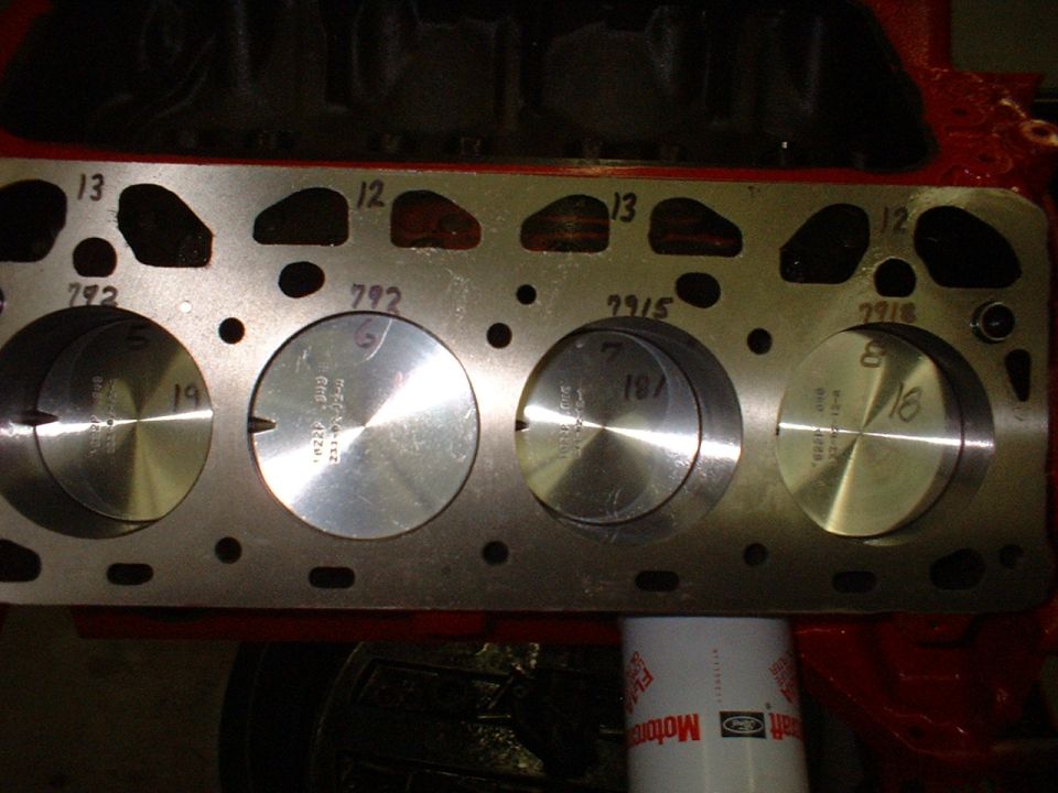 Engine block with four pistons visible, showing numbers 13, 12, 792, 2915, and 2918 stamped on the metal