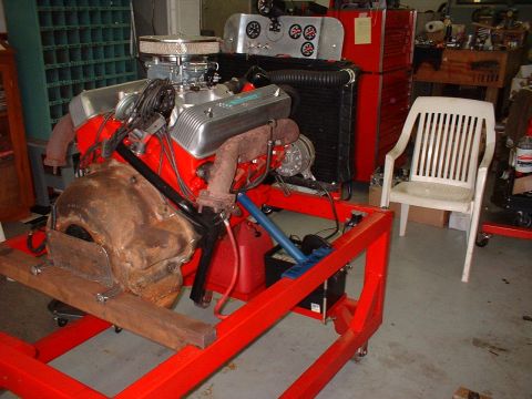 1955 Ford Thunderbird - A V8 engine is mounted on a red stand, likely for repair or display in a garage setting.