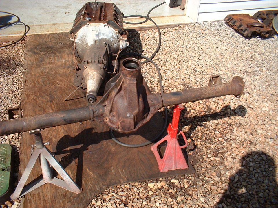 Engine and rear axle assembly on plywood, supported by jack stands