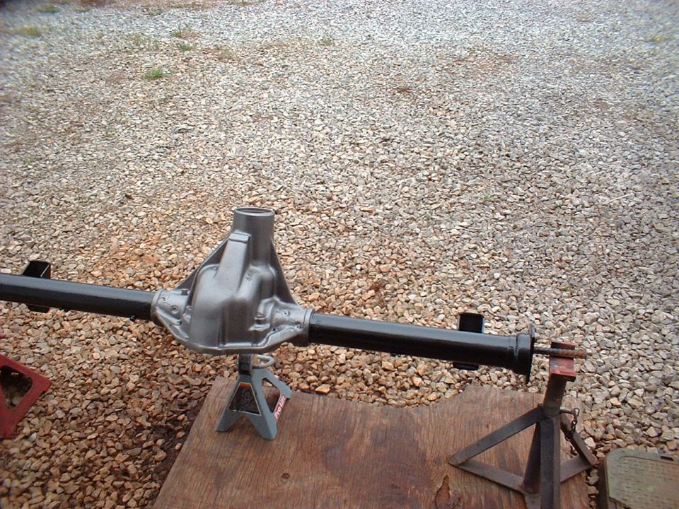 Rear axle assembly on jack stands, outdoors on gravel