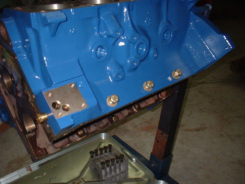 Blue engine block on stand with bolts in tray