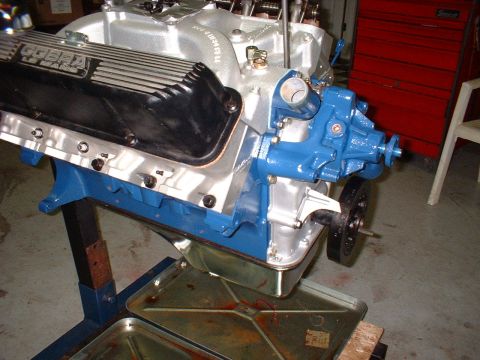 1967 Ford Mustang - A Ford Cobra engine is shown on an engine stand with a blue water pump and black valve covers.