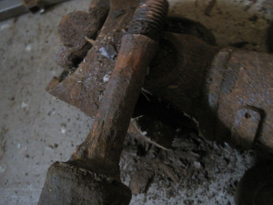 Close-up of a heavily rusted metal suspension component with a threaded bolt