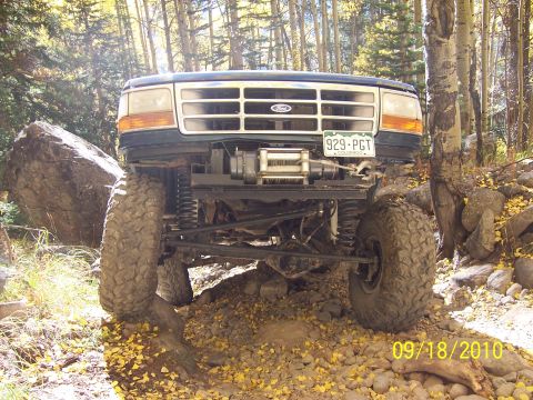 1994 Ford Bronco - 1994 Ford Bronco on a rocky trail with trees and fallen leaves.