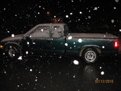 1986 Ford Bronco - A green pickup truck is parked outside during a snowfall at night.