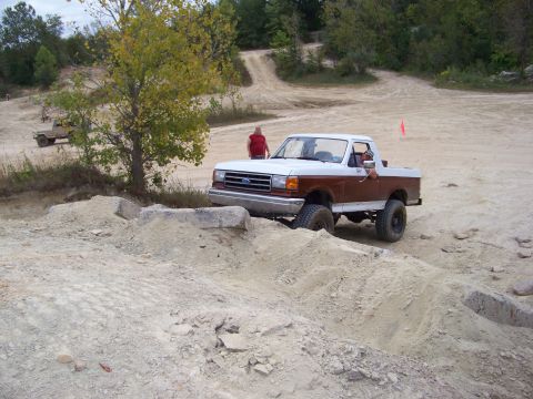1989 Ford Bronco - This 1989 Ford Bronco is shown off-roading on a dirt track with a person standing nearby.